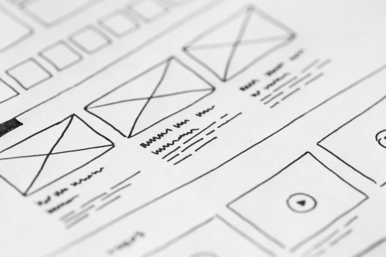 A detailed, close-up shot of a hand-sketched wireframe layout on paper for a user experience project.